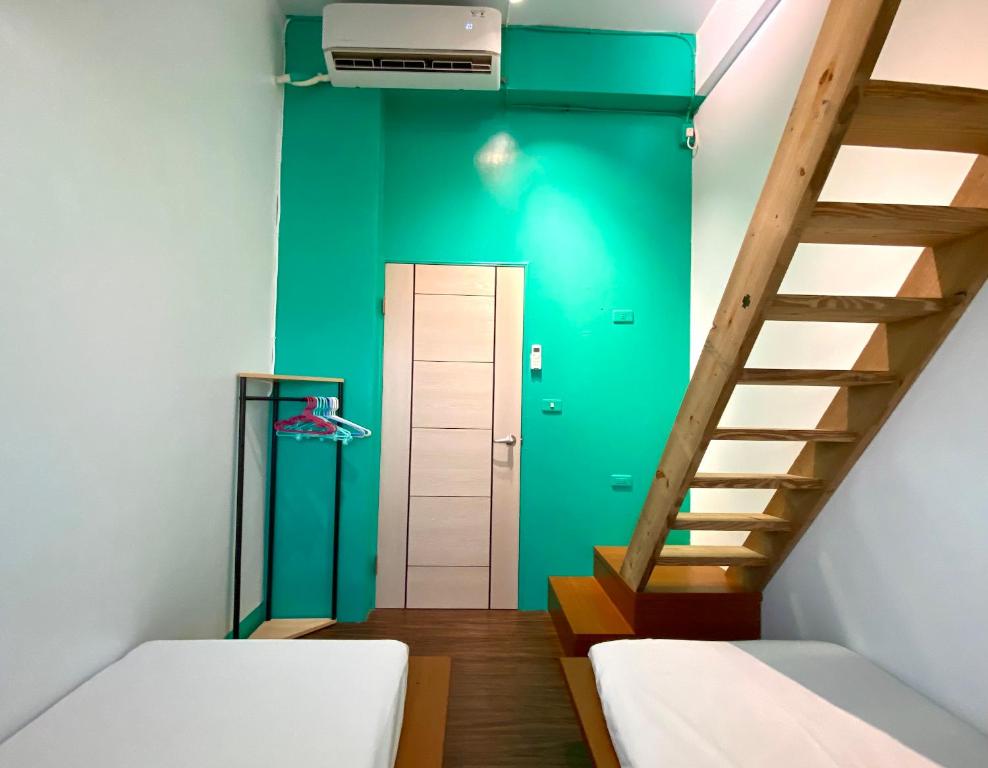 a room with two beds and a green wall at 澎湖北吉光背包客民宿 Bayhouse Hostel Penghu in Magong