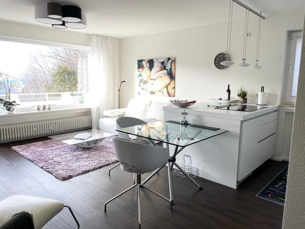 een keuken en een woonkamer met een glazen tafel bij Modernes Apartment mit traumhaftem Sunset Blick in Baden-Baden