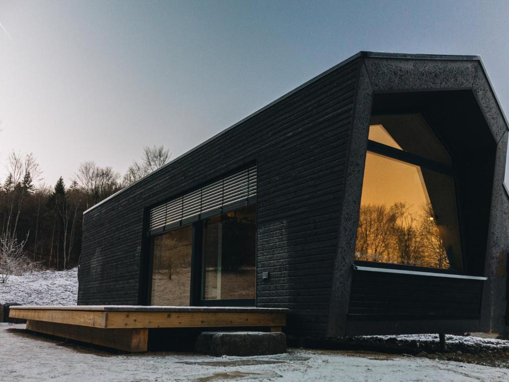 a small black house with a large window at Cabin Westerwald Sauna zubuchbar in Niederdreisbach