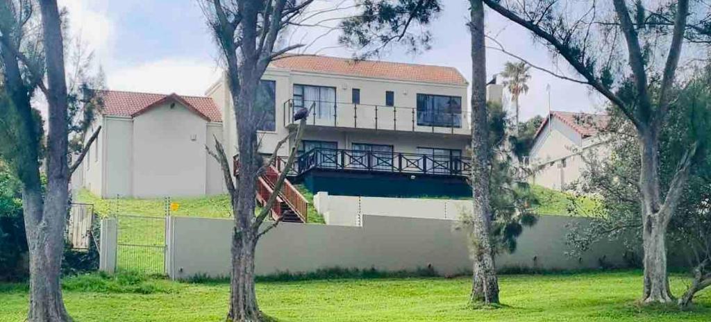 a house with a balcony in a yard with trees at Ndaba Golf Lodge on 13th hole in East London