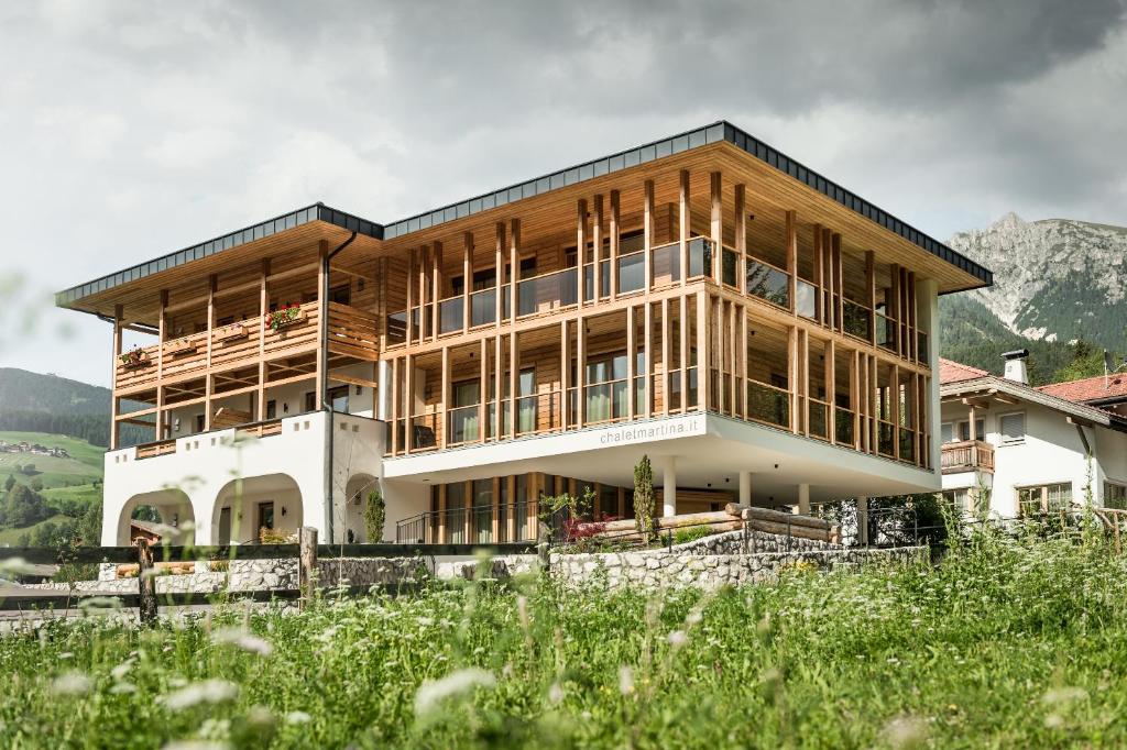 a house on a hill with mountains in the background at Chalet Martina Apartments in San Vigilio Di Marebbe