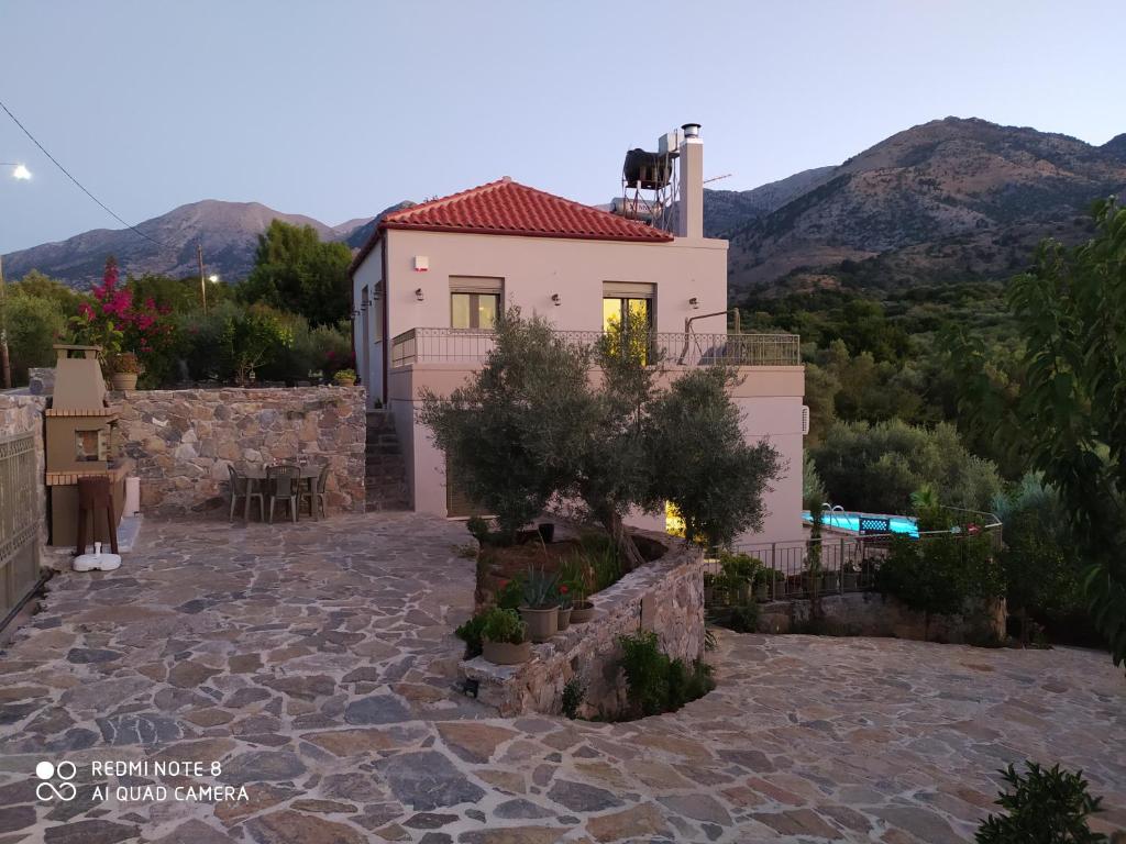 una casa en una colina con montañas en el fondo en "Villa Kastania" Melidoni, Crete, en Melidhónion