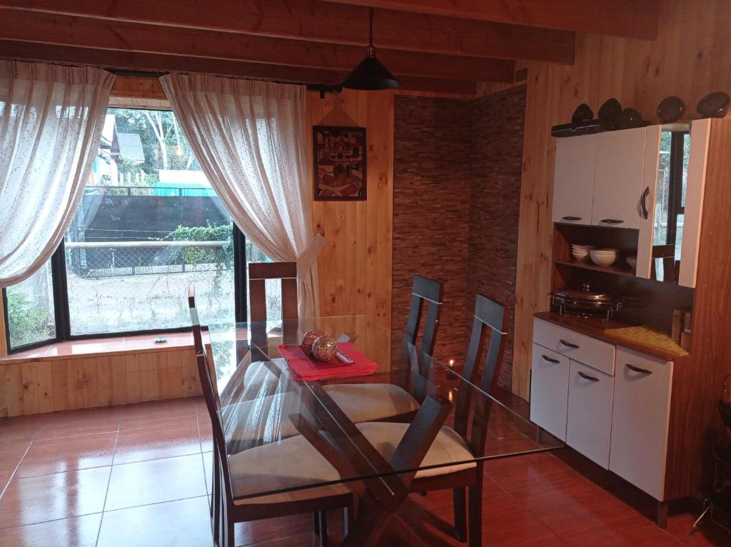 a living room with a table and a kitchen at Cabaña Coñaripe in Coñaripe