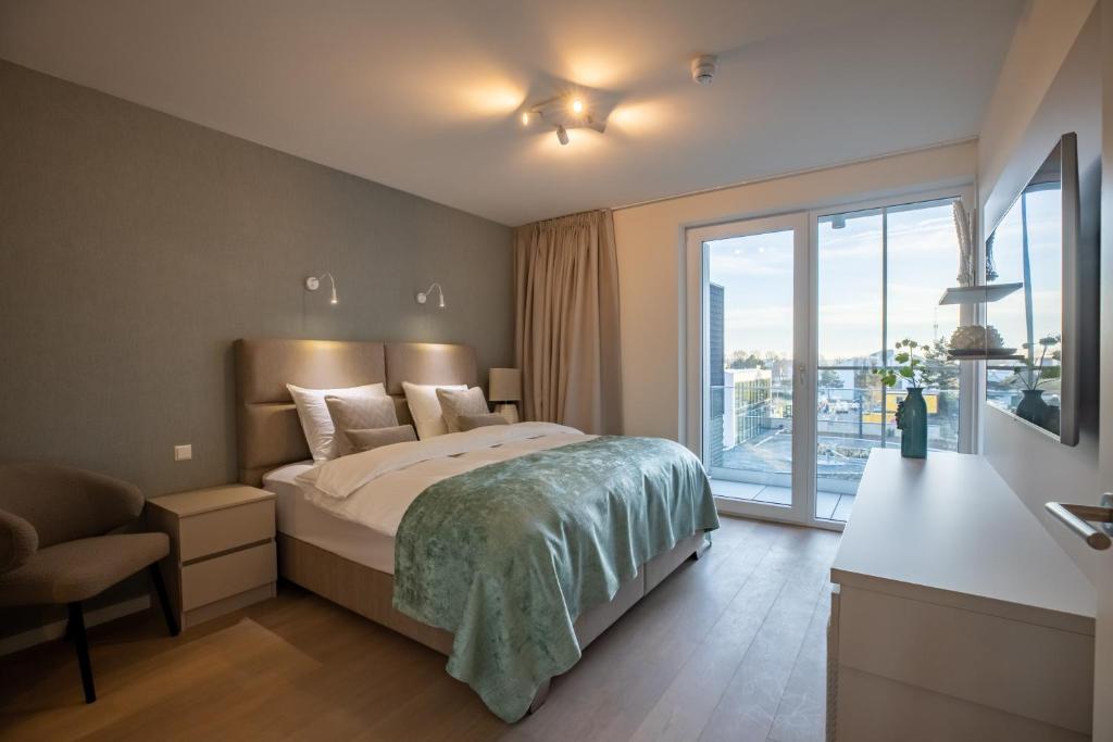 een slaapkamer met een bed en een groot raam bij The Sailor, full sea view, use of hotel swimming pool and sauna in Cadzand