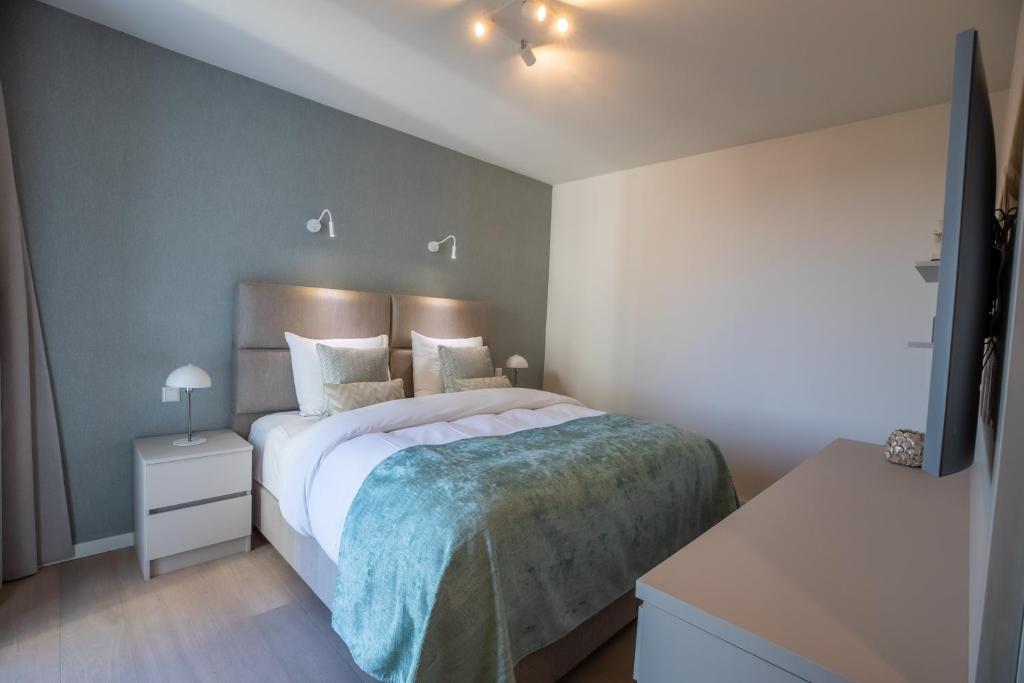 um quarto com uma grande cama branca e uma mesa de cabeceira em By Sea, Full Sea View, balcony, use of hotel Pool and Sauna em Cadzand