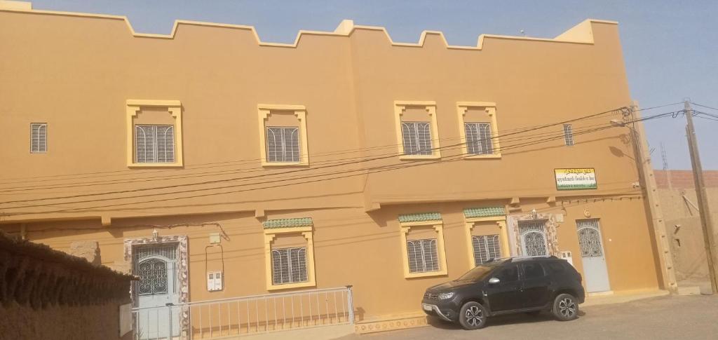 メルズーガにあるAppartement merzougaの黄色い建物の前に停車する車