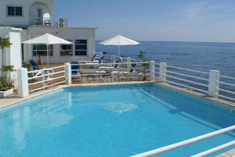 a large blue swimming pool next to the ocean at Hotel Ariana in Marine du Miomo