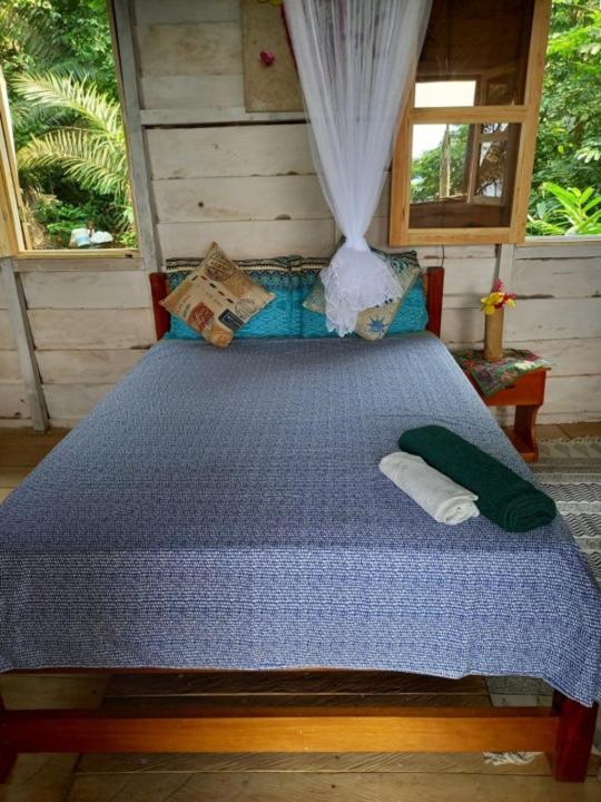 a bedroom with a bed with a blue comforter at World's View Wild Camping Salaszoi, Principe Island in Santo António