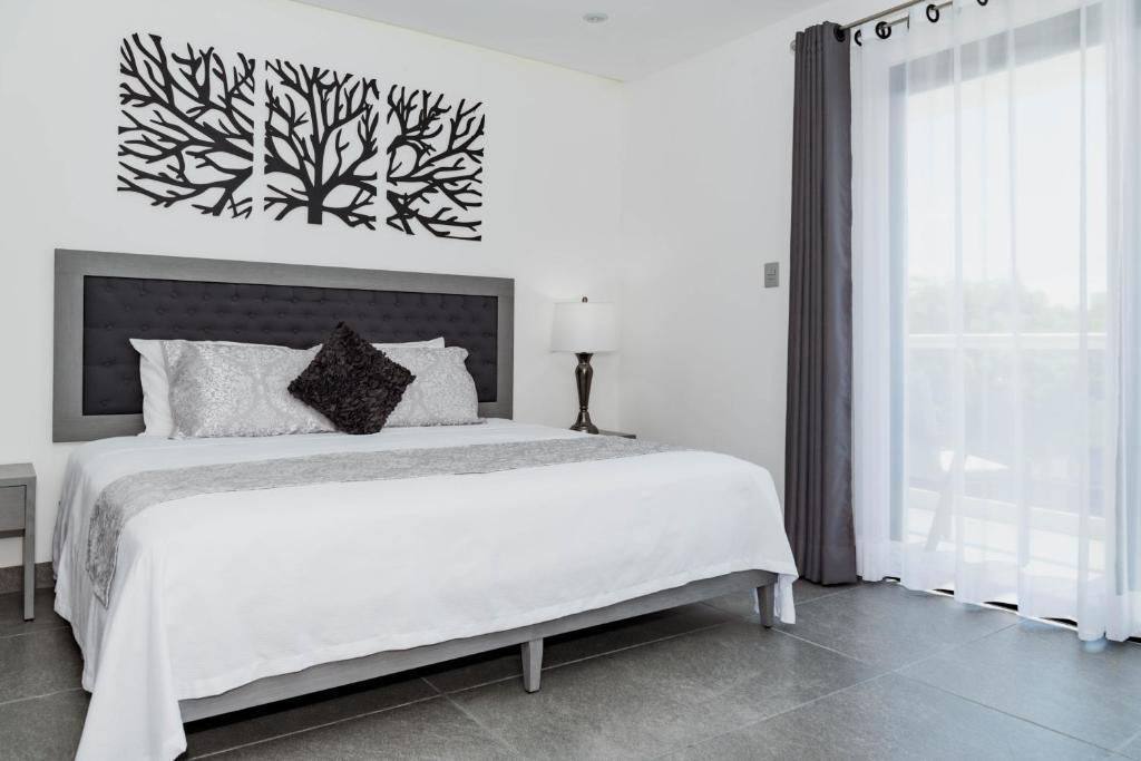a white bedroom with a large bed and a window at Dreams Apartments 7. Loft a 9 minutos de la playa in Isla Mujeres