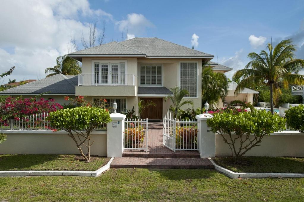 una casa con una cerca blanca delante de ella en Long Island Breeze Compound home en Nassau