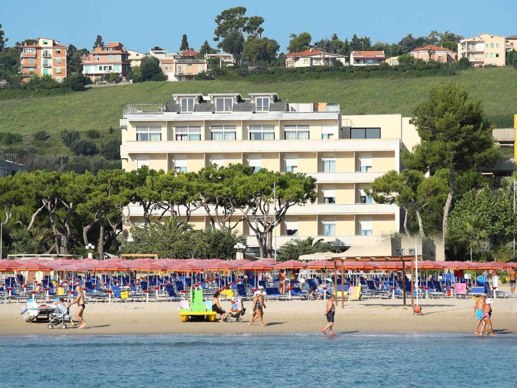 een groep mensen op een strand met parasols bij Hotel Cristallo in Giulianova