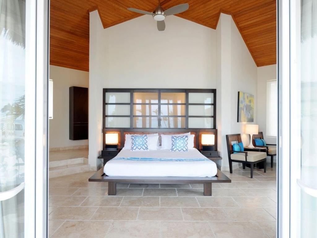 1 dormitorio con 1 cama grande y ventilador de techo en Sky Beach Club Bungalow cabin, en Governorʼs Harbour