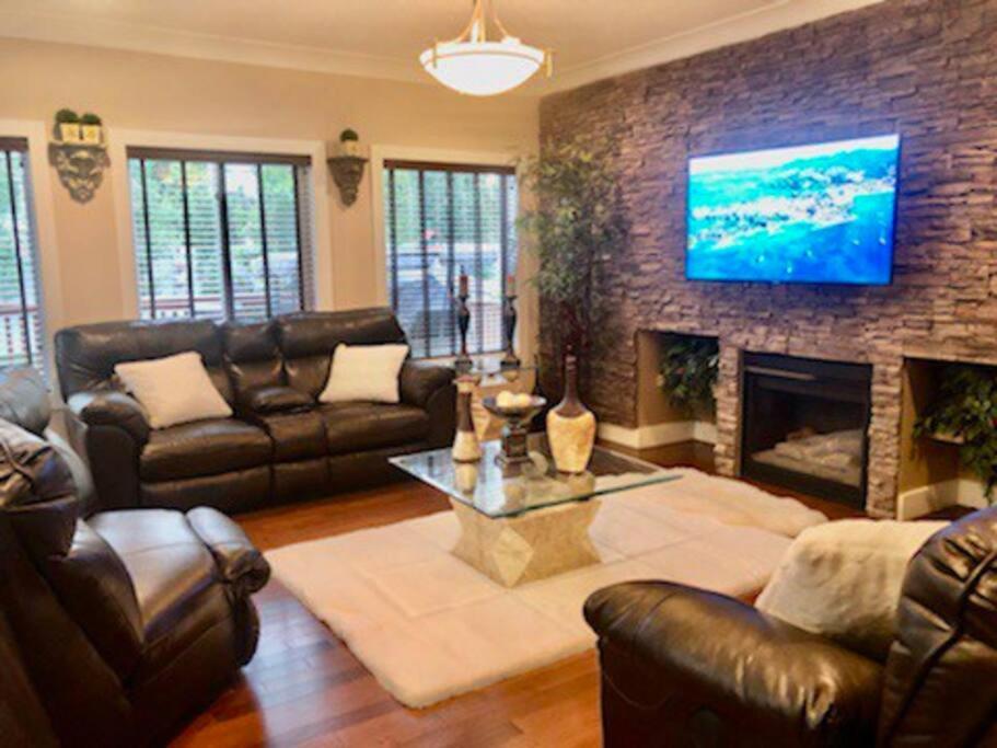 a living room with leather furniture and a fireplace at Luxury 3700 sq/ 5 bedroom/ jettedtub/ 4 fireplaces in Edmonton