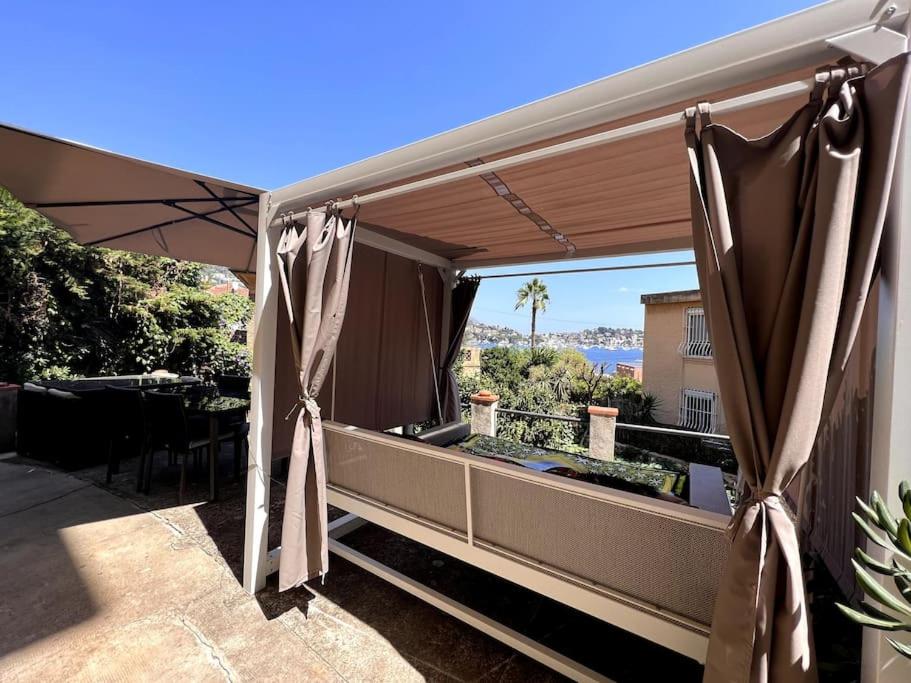 d'un balcon avec des rideaux et une vue sur l'océan. dans l'établissement Magnifique appartement avec vue mer à Villefranche, à Villefranche-sur-Mer