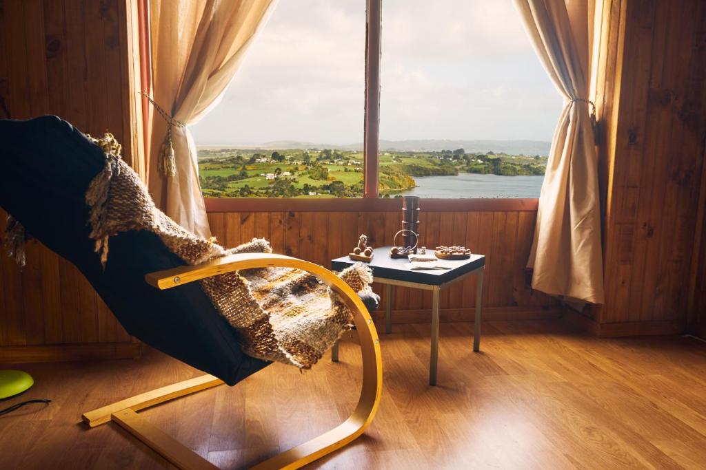 Habitación con silla y mesa frente a una ventana en CABAÑA AZUL Y VERDE, en Ancud