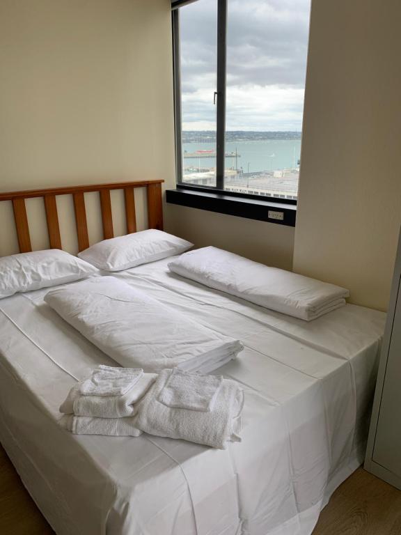 uma cama branca com toalhas num quarto com uma janela em Garden Hostel em Auckland