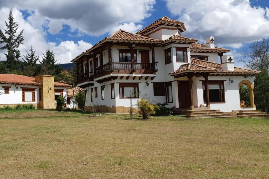 ein großes weißes Haus mit einem großen Hof in der Unterkunft Hermosa cabaña rural Portal de Alejandría in Villa de Leyva