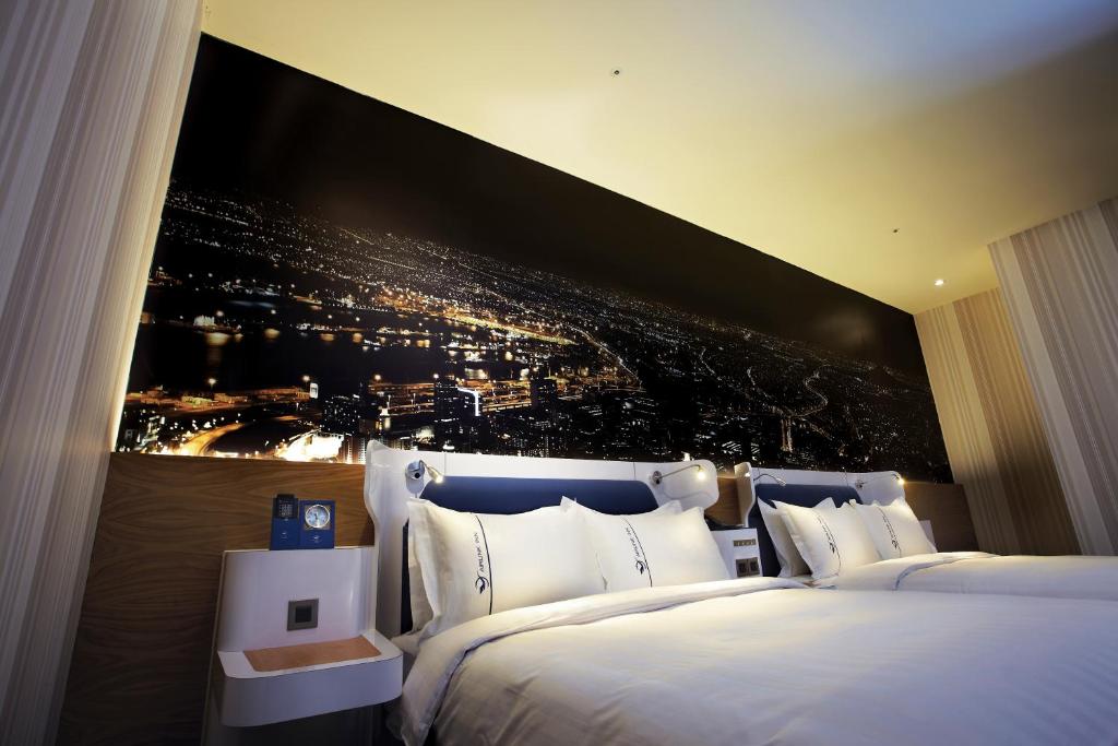 a bedroom with two beds with a large painting on the wall at Airline Inn Green Park Way in Taichung