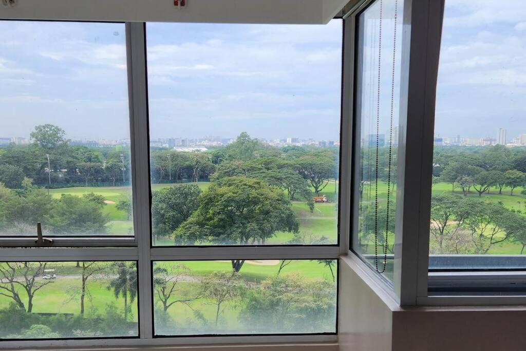 a room with four windows looking out at a park at Enjoy BGC Sunset and Golf Course View 2 BR Loft with 100mbps Internet Connection in Manila