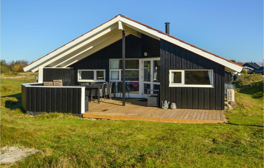 a black house with a wooden porch and a deck at Awesome Home In Fan With 3 Bedrooms, Sauna And Wifi in Fanø