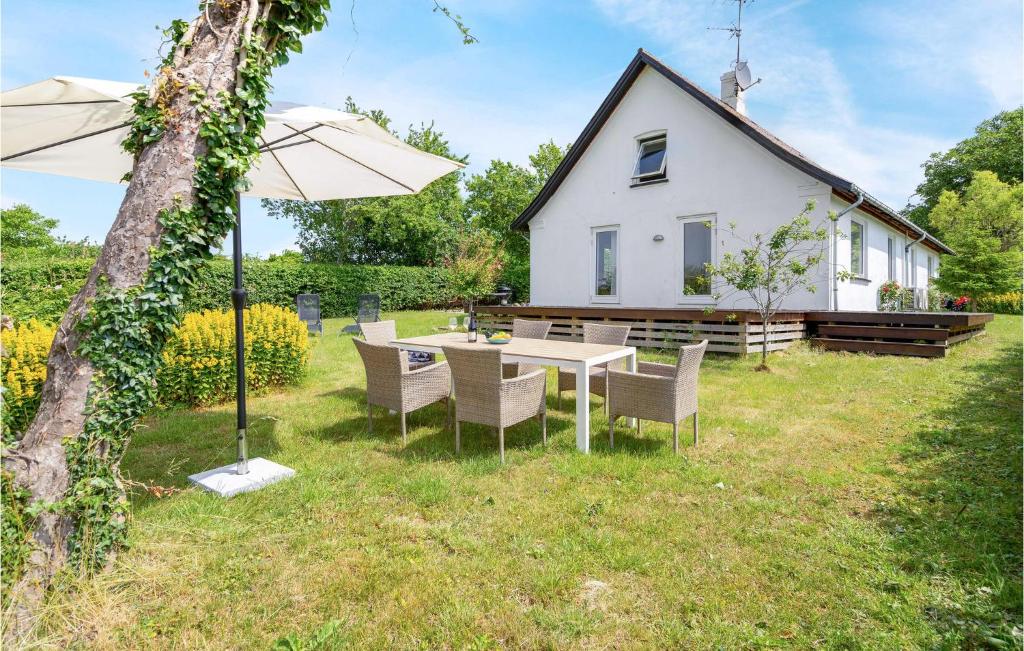 una mesa con sillas y una sombrilla frente a una casa en Lovely Home In Stege With Kitchen, en Stege