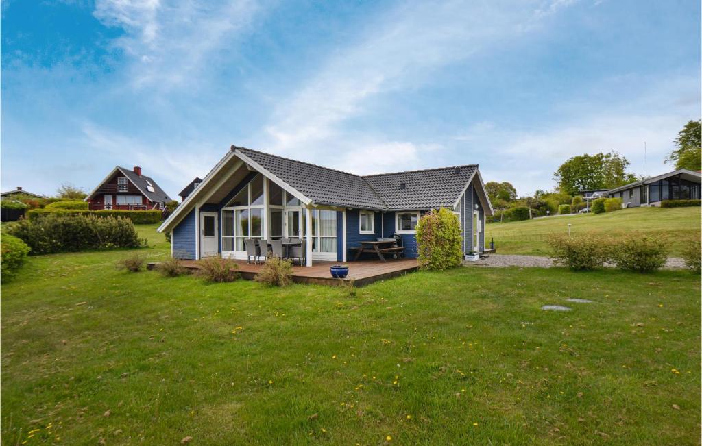 a small blue house with a large yard at Nice Home In Glesborg With House Sea View in Bønnerup Strand