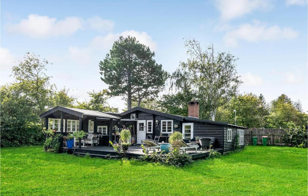 ein schwarzes Haus in einem Garten mit grünem Gras in der Unterkunft Nice Home In Tisvildeleje With Kitchen in Tisvildeleje