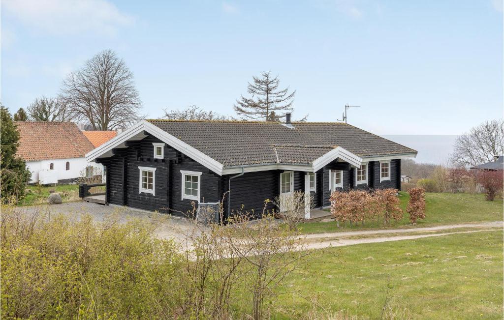 a black house in a field next to a house at 3 Bedroom Gorgeous Home In Hasle in Hasle