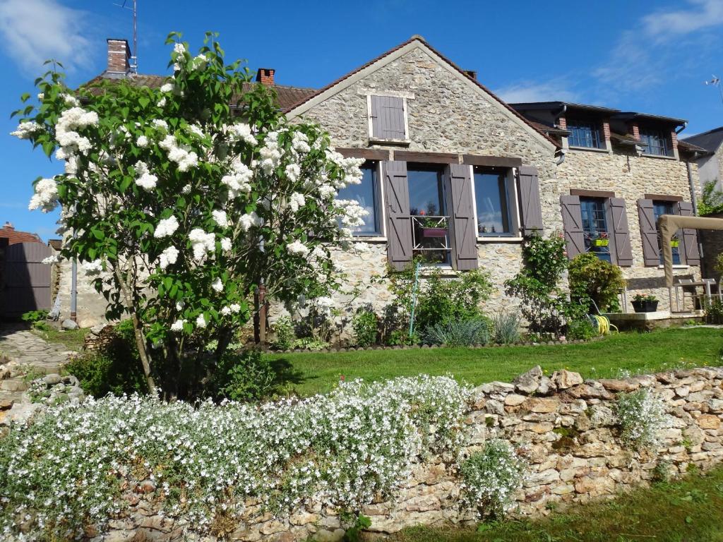 a house with a flowering tree in the yard at La maison du Fargis in Auffargis