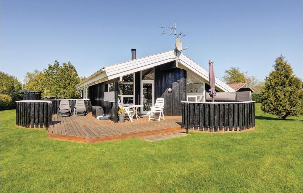una casa con terraza y sillas en un campo en Stunning Home In Hadsund With Kitchen, en Øster Hurup