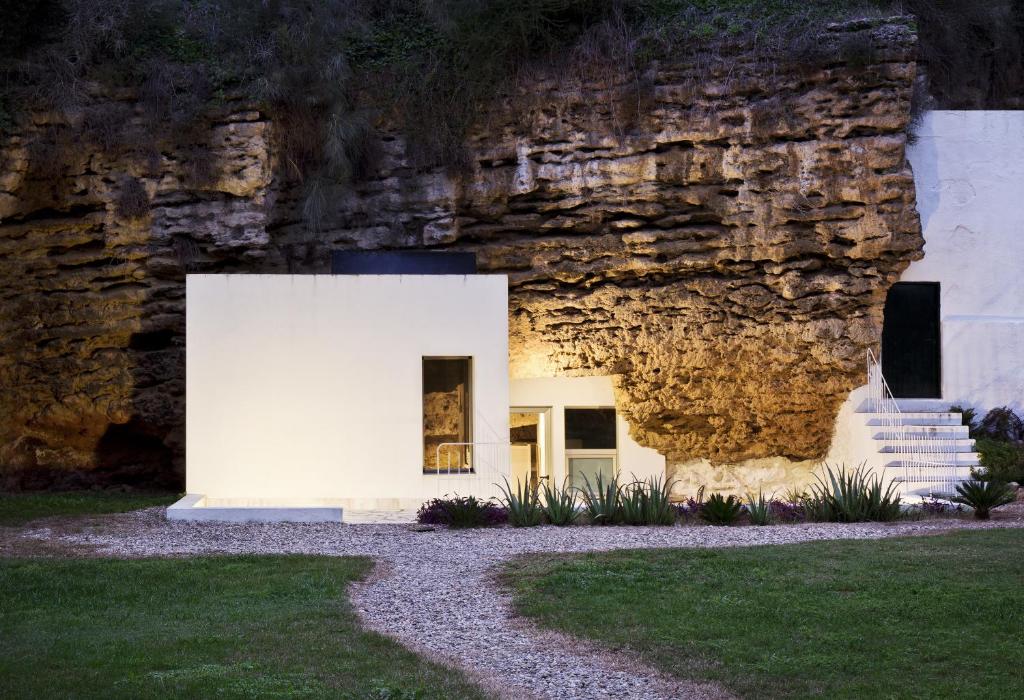 een huis gebouwd aan de zijkant van een rotswand bij Cuevas del Pino Turismo Rural y Emocional SL in Villarrubia
