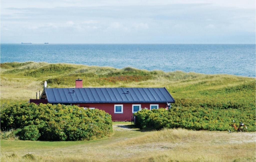 スケーエンにあるBeautiful Home In Skagen With 2 Bedrooms And Wifiの海辺の丘の横の赤い家