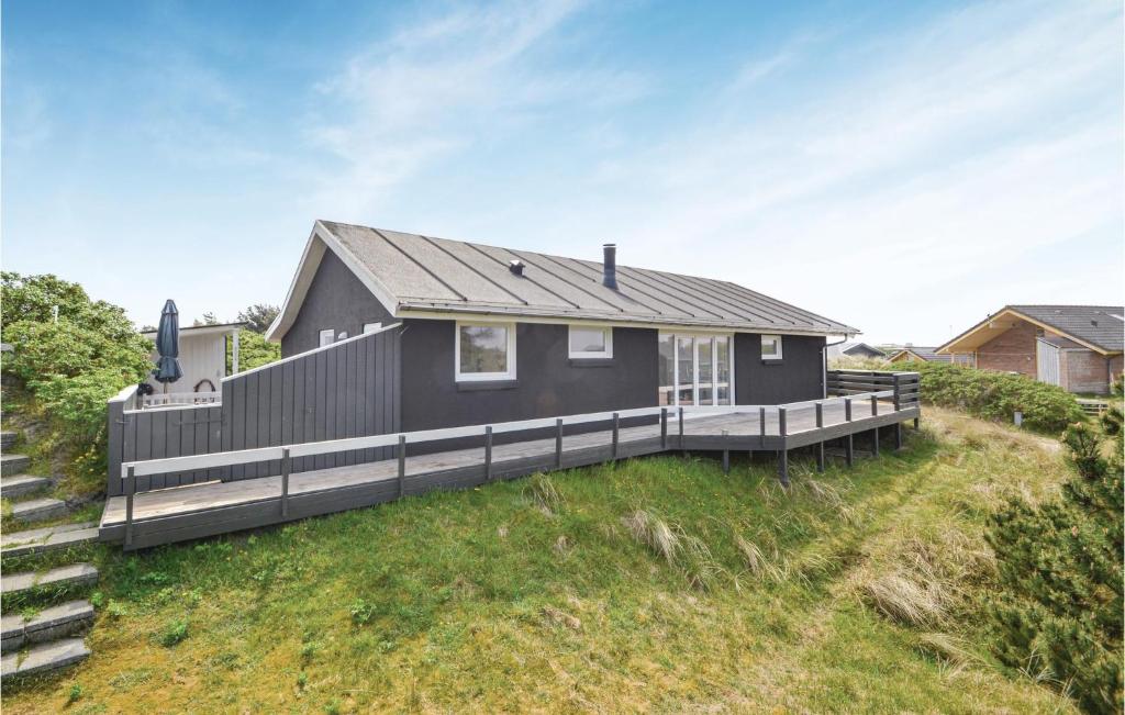 een zwart huis op een heuvel met een terras bij Cozy Home In Fan With Kitchen in Fanø