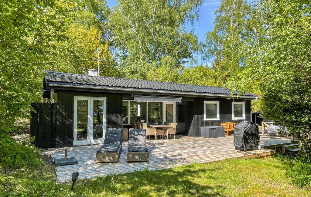 a small house with a wooden deck in a yard at Amazing Home In Aakirkeby With House Sea View in Vester Sømarken