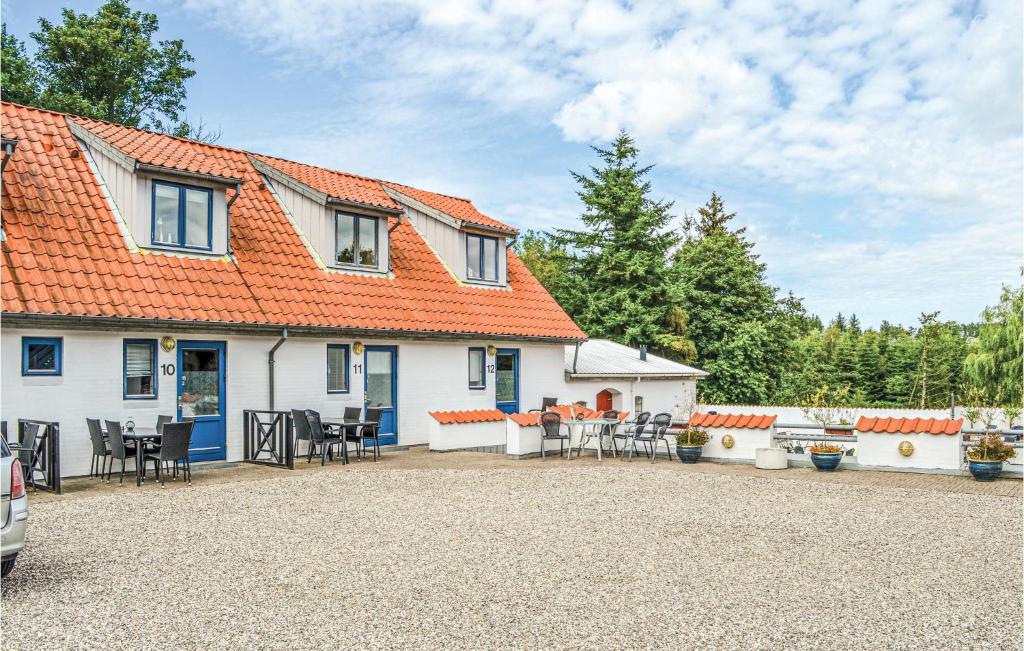 エーベルトフトにあるNice Apartment In Ebeltoft With 3 Bedrooms, Wifi And Outdoor Swimming Poolのオレンジ色の屋根と椅子が備わる白い家