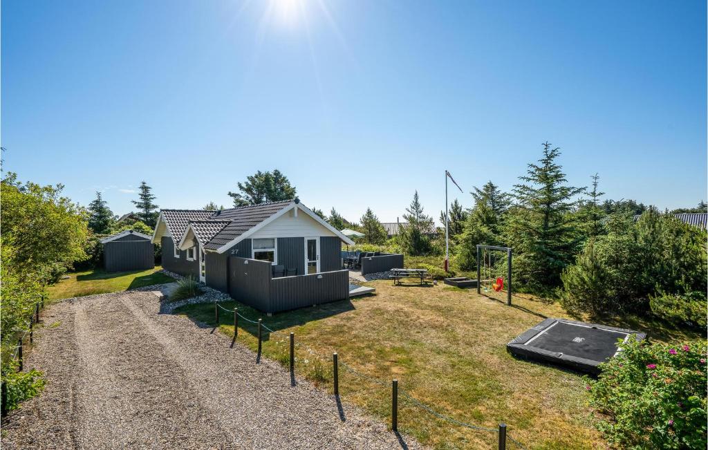 a small house in a yard with a gravel driveway at Holiday Home Kirksvej Hvide Sande Iv in Bjerregård