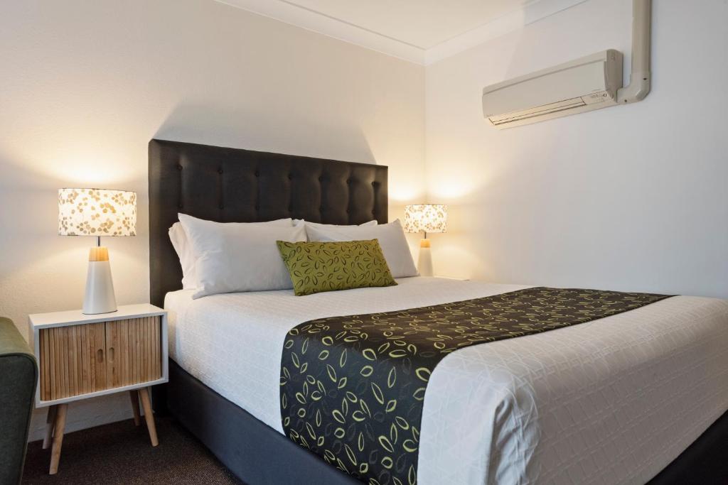 a bedroom with a large bed and a night stand at Bomaderry Motor Inn in Nowra