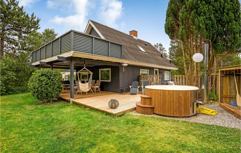 ein Haus mit einer Holzterrasse mit Whirlpool in der Unterkunft Holiday Home Telefonvejen X in Fjellerup Strand