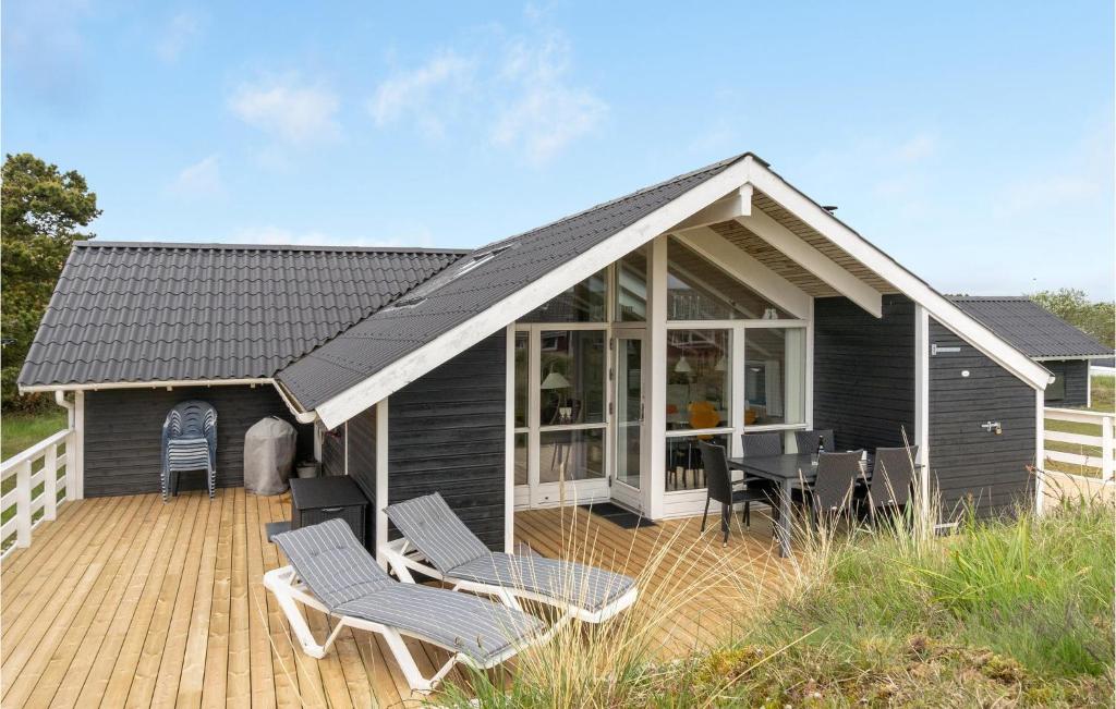 una casa nera con sedie su una terrazza in legno di Cassiopeia a Fanø