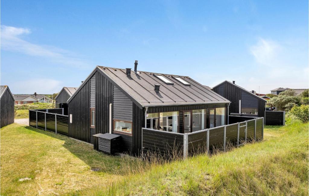 a black house on top of a grass field at Nice Home In Rm With 2 Bedrooms And Wifi in Bolilmark