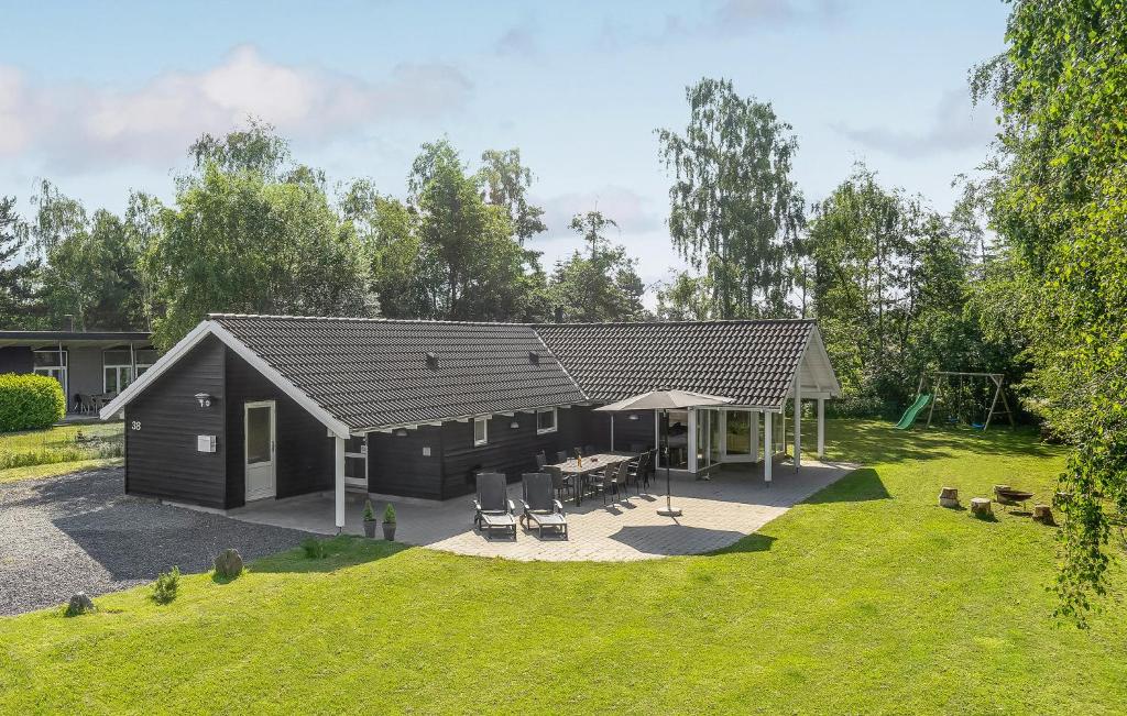 een zwarte schuur met een patio en een speeltuin bij Nice Home In Vggerlse With 5 Bedrooms, Sauna And Wifi in Bøtø By