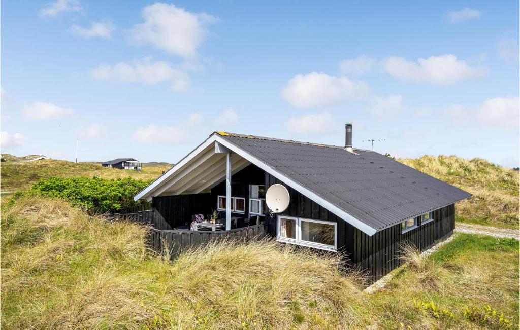 哈夫維格Holiday Home Kr Madsens Vej Hvide Sande Denm的田野中央的一座黑色房子