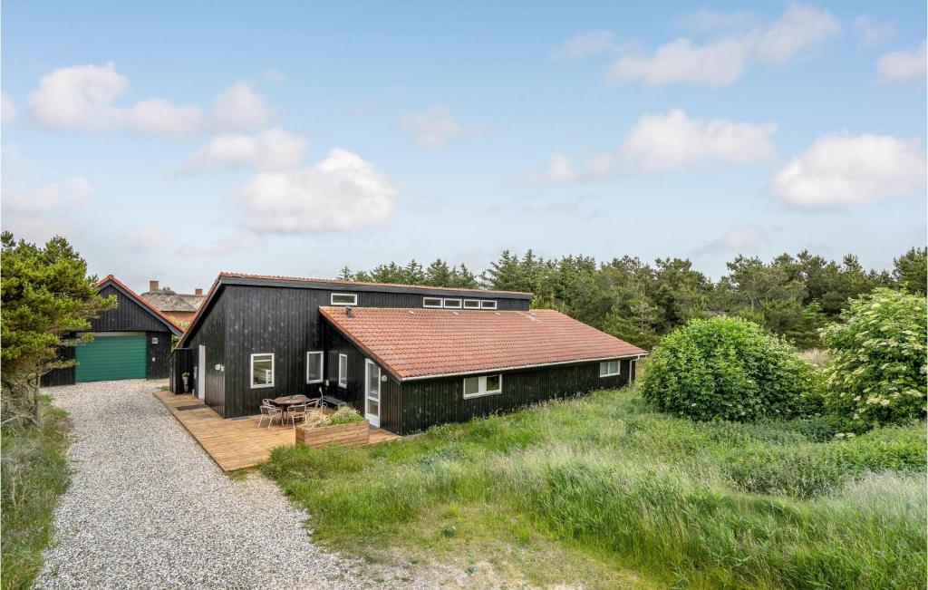 a black house with a red roof at Amazing Home In Ringkbing With 5 Bedrooms, Sauna And Wifi in Klegod