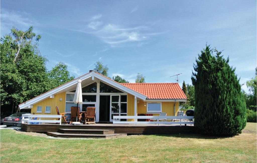 a small yellow house with a large deck at Holiday Home Kamillevej Tranekær X in Skattebølle
