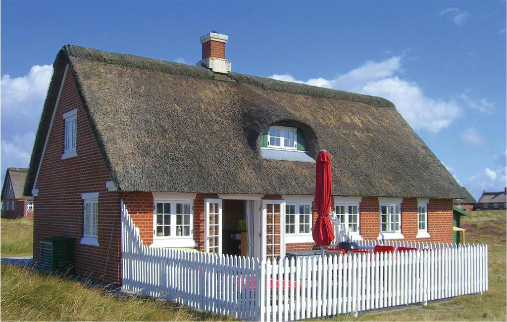 una casa con tetto di paglia e recinzione bianca di Beautiful Home In Fan With Sauna a Sønderho