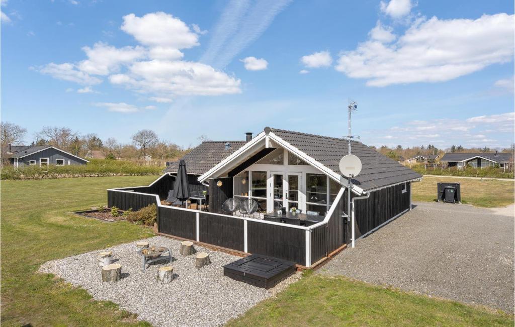 una casa negra con techo en un campo en Lovely Home In Hemmet With Kitchen, en Hemmet