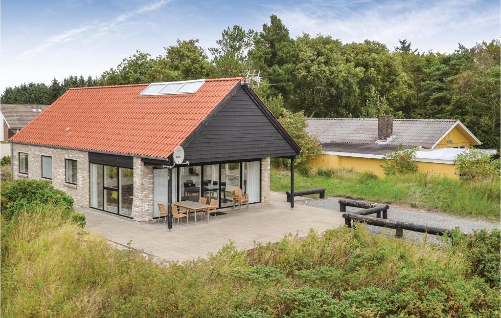 una casa con tetto rosso e patio di Three-Bedroom Holiday Home In Blavand a Blåvand