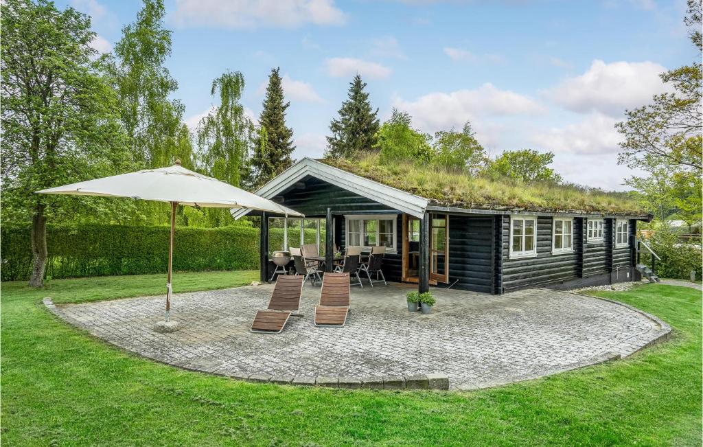 uma cabana com um telhado de relva com cadeiras e um guarda-sol em 2 Bedroom Lovely Home In Jgerspris em Hornsved