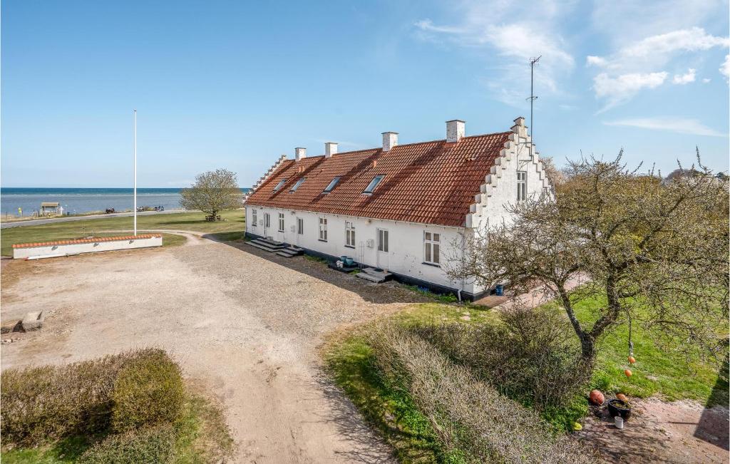 una casa bianca con un tetto rosso accanto all'oceano di Amazing Apartment In Allingbro With Wifi a Allingåbro