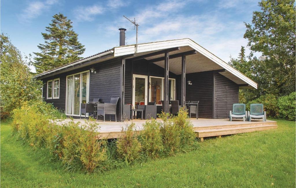 una pequeña casa negra con 2 sillas en una terraza en Cozy Home In Knebel With Wifi, en Knebel